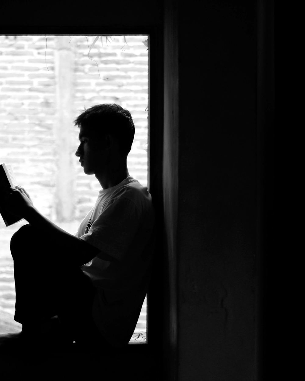 A man reading in the light of a doorway